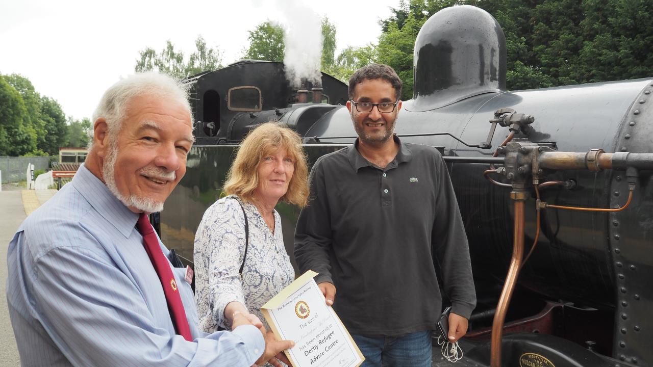 John Snell, Chairman of WyvernRail plc, presenting a certification of donation to Janet Fuller and Ahmed, both of Derby Refugee Advice Centre at Duffield station