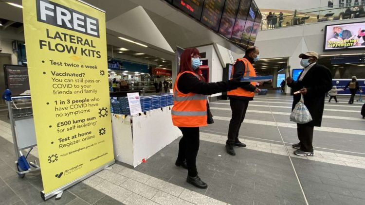 Lateral flow test kits being handed out on Birmingham New Street station's concourse