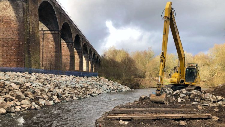 Reddish Vale viaduct with digger to move the 5,500 tonnes of boulders for the river erosion work