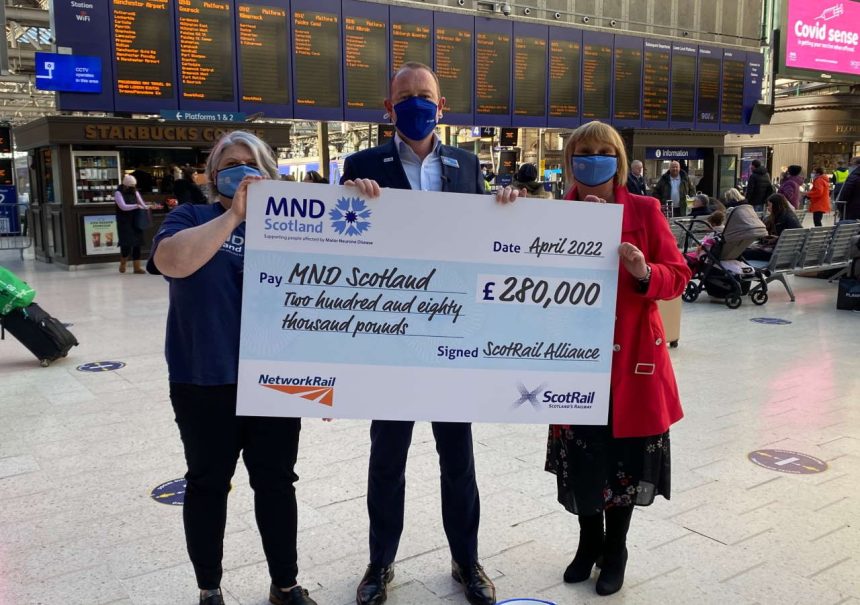 Sophie Nightingale, ScotRail Community Investment Manager and Alex Hynes, Scotland's Railway Managing Director, presenting cheque to Morag McGown, MND Scotland Corporate Partnerships Manager at Glasgow Central station