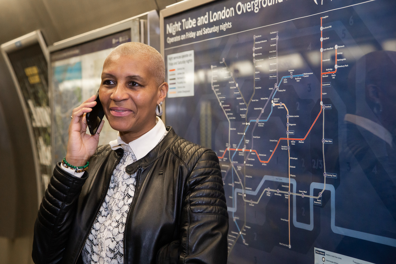 Making a phone call on the Underground in front of a Night Tube map