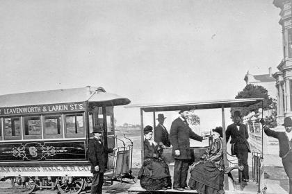 Clay Street Hill Cable Car at Clay Street and Van Ness Avenue circa October 1877. Andrew Hallidie stands on the open-air cable car between two seated women