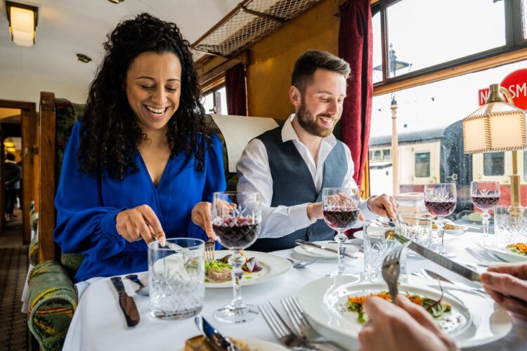 A couple are enjoying fine dining on board a luxury carriage.