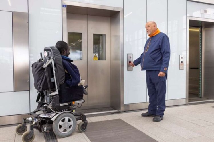 Staff assisting wheelchair user to use lift