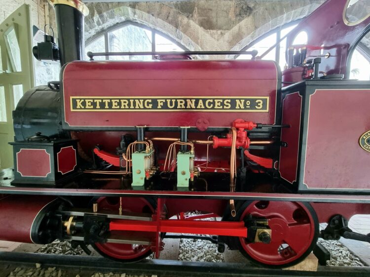 Kettering Furnace No. 3 is shown side on. It is in a red livery and is a 0-4-0 Saddle Tank. 
