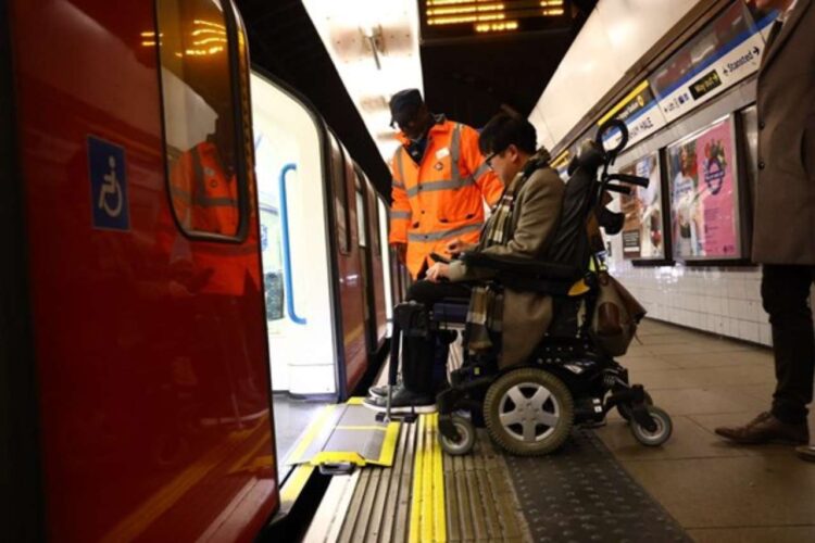 Staff assist a wheelchair user onto a train
