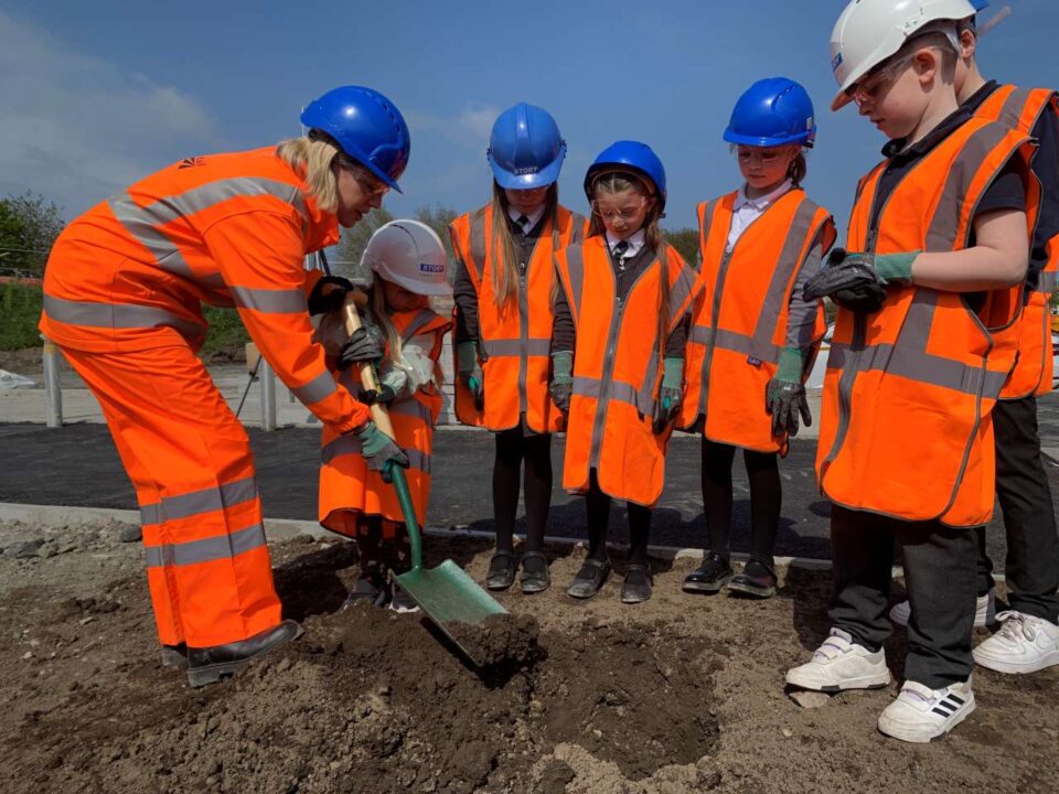 Jenny Gilruth MSP helps a pupil from Parkhill Primary School bury their time capsule at Leven station, while other pupils look on.