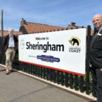 Sheringham station welcome sign From left Chris Mitchell and David Pearce from Bittern Line CRP and Alan Neville from Greater Anglia. Credit: Bittern Line CRP