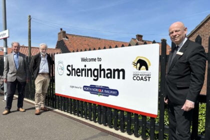 Sheringham station welcome sign From left Chris Mitchell and David Pearce from Bittern Line CRP and Alan Neville from Greater Anglia. Credit: Bittern Line CRP